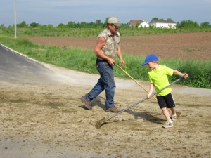 Father and son clean the road after the herd crossed it heading to pasture.